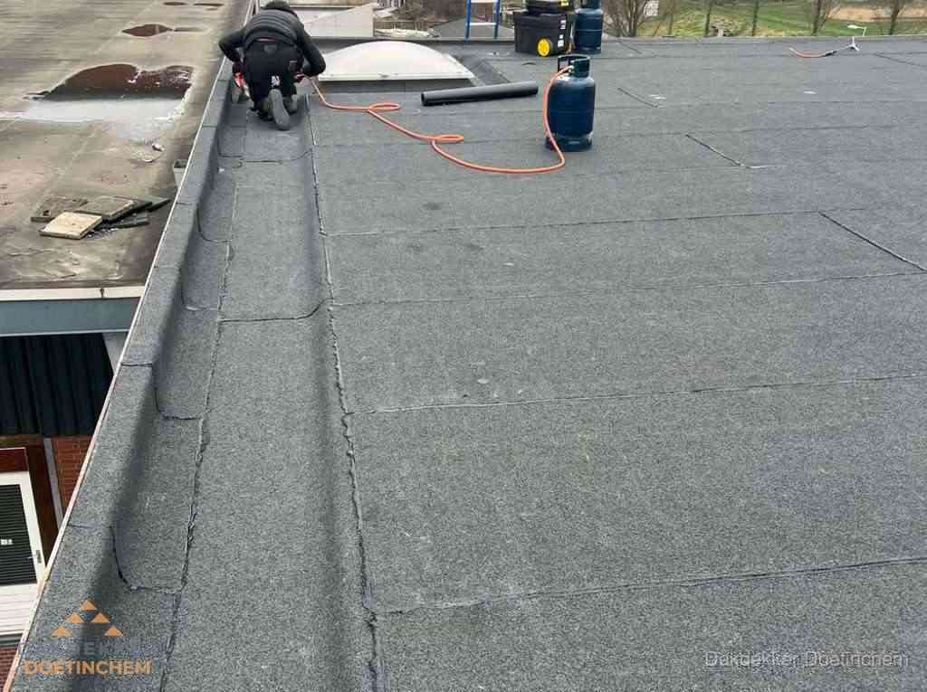 Dakdekker repareert bitumen dakbedekking op groot plat dak in Doetinchem